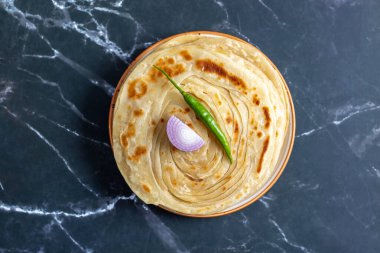 Çıtır çıtır, gevrek laccha paratha dilimlenmiş soğan, kırmızı kırmızı biber ve keskin turşu ile sıcak servis edilir. Mükemmel bir doku ve kalın tatlar karışımı yaratır..