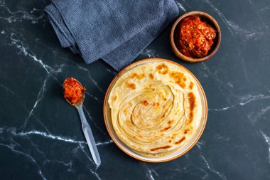 Çıtır çıtır, gevrek laccha paratha dilimlenmiş soğan, kırmızı kırmızı biber ve keskin turşu ile sıcak servis edilir. Mükemmel bir doku ve kalın tatlar karışımı yaratır..