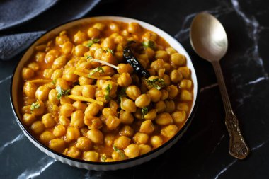Kabuli Chana Masala, zengin ve sağlıklı bir kıvamda kaynatılmış nohut, domates, soğan ve aromatik baharatlarla yapılan lezzetli bir Kuzey Hint körisidir..