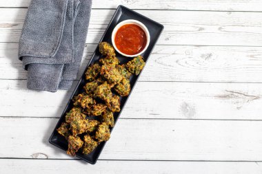 Palak ke pakore gevrek, bol yağda kızartılmış ıspanaklı börek besan, baharat ve taze ıspanak yapraklarıyla yapılır, acılı ve çay ile servis edilir..