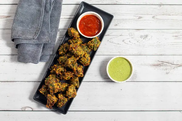 Palak ke pakore gevrek, bol yağda kızartılmış ıspanaklı börek besan, baharat ve taze ıspanak yapraklarıyla yapılır, acılı ve çay ile servis edilir..