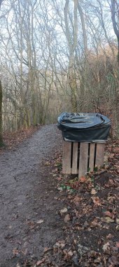 Trash bin in the forest on the trail side. Winter, early spring european forest landscape. High quality photo clipart