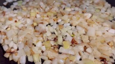 Kızartma tavasında doğranmış beyaz soğanı yağda kızartırken çekilmiş makro yatay videoyu kapat. 16: 9 'da. Yüksek kalite 4k görüntü