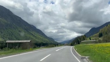 Seyahat ediyorum. Dağlardaki bir yolda giden bir arabanın bakış açısı. Arka planda bulutlu gökyüzü olan Alplerde sür. Yüksek kalite 4k görüntü