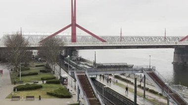 2025.03.16 yılında Budapeşte Macaristan 'daki Tuna Köprüsü' nün altındaki tren istasyonu. Tren kalkıyor, yolcular yağmur altında yürüyor. Yüksek kalite 4k görüntü