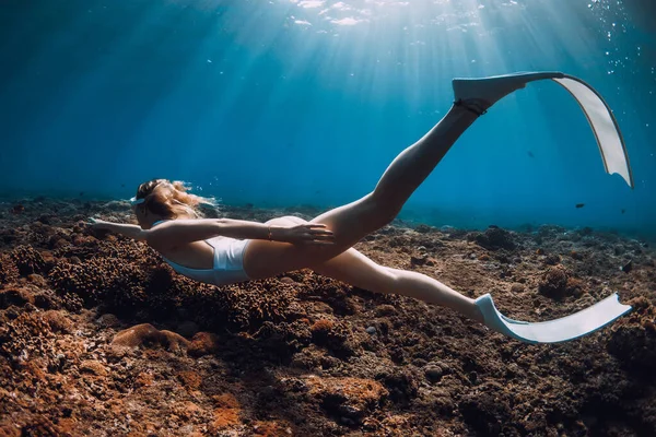 白い水着の女性のフリーダイバーは サンゴの上にフィンとダイビングを着用します 青い海でのフリーダイビング — ストック写真