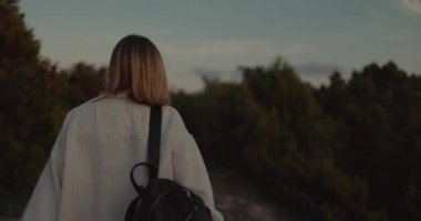 Doğada gün batımı ışığıyla yürüyen bir kadın. Dağlarda tatil.