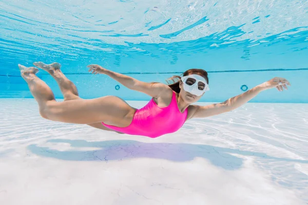 Young woman in bright bikini swimming underwater in pool