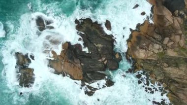 Brezilya 'da kayalar, dalgalar ve köpüklerle dolu bir sahil şeridi. Hava görünümü