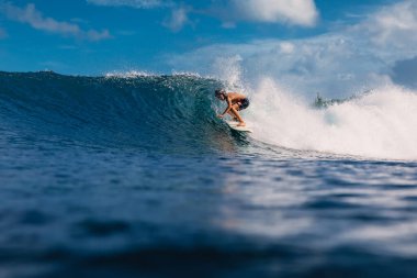 4 Ocak 2023. Bali, Endonezya. Sörf yaparken tropikal okyanusta küçük bir çocuk. Sörfçü varil dalgasında sörf tahtasında.