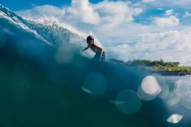 4 Ocak 2023. Bali, Endonezya. Sörf yaparken tropikal okyanusta küçük bir çocuk. Sörfçü varil dalgasında sörf tahtasında.