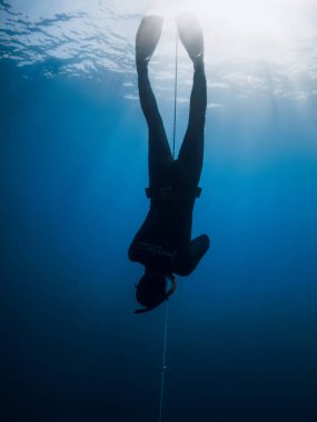 October 03, 2022. Amed, Indonesia. Men in wetsuit with fins training dive on deep in blue ocean. Professional freediving underwater in transparent sea