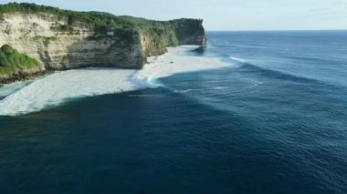 Aerial view of scenic coastline with cliffs, ocean with ideal waves in Uluwatu, Bali