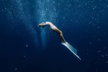 Freediver posing underwater with air bubbles. Freediving with beautiful girl in ocean