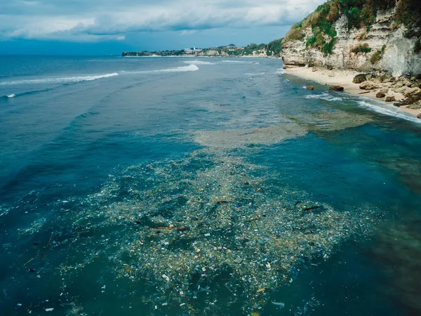 Indian ocean in Bali and plastic trash, aerial view. Dirty plastic bottles and bags on a garbage. Ocean pollution, plastic in water.