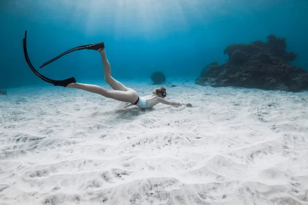 Free diver girl in white swimwear dive and exploring sea life. Freediving in blue ocean