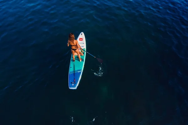 2022年7月24日 土耳其安塔利亚一个身材苗条的女人 带着孩子划船站在安静的海面上的桨板上 在海上红色垫板上有小女儿的妇女 — 图库照片