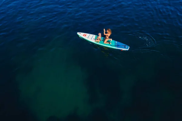 2022年7月24日 トルコのアンタルヤ 静かな海でスタンドアップパドルボードに子供を漕ぐスリム女性 女とともに子供娘オン赤パドルSupボード上の海 — ストック写真