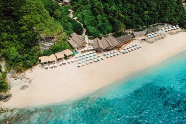 Mavi okyanus manzarası ve Bali 'de şemsiyeli lüks sahil beldesi.