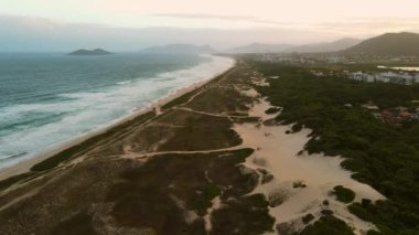 Campeche, Florianopolis 'te kum tepeleri, okyanus ve gün batımı tonları olan bir sahil.