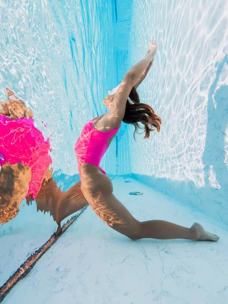 夏休みには プールで水中でピンクのセクシーな水着で魅力的な若い女性がポーズをとって日焼けします 健康な体のケア — ストック写真