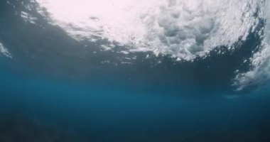 Mavi okyanusta su altında dalga kırılıyor. Güçlü fıçı dalgasının sualtı görüntüsü