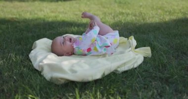 Bahçede gülümseyen ve uzanan tatlı bir kız bebek. Dışarıda mutlu duyguları olan bir bebek.