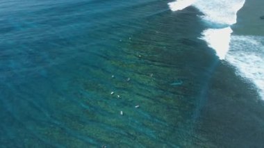 Dalgalar ve sörfçülerle dolu mavi bir okyanus. Hava görünümü