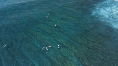 Mavi şeffaf okyanus, dalgalar ve sörfçüler sıraya dizildi. Hava görünümü