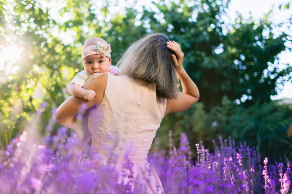 妈妈带着她的女儿在户外带着薰衣草花和阳光 — 图库照片