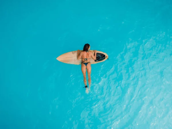 青やターコイズの海でサーフボード上のビキニのサーフガール セクシーなサーファー女性の空中ビュー — ストック写真