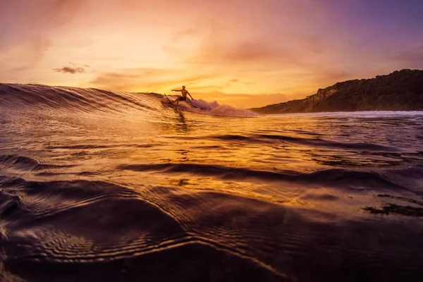 2022年12月14日 インドネシアのバリ 日没または日の出の色調でサーフィン中の熱帯の海の男 波のサーフボード上のサーファーに乗る — ストック写真