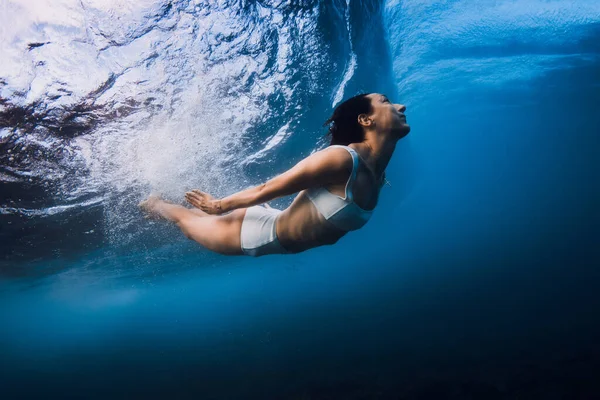 Woman dive without surfboard underwater with ocean wave. Duck dive under barrel wave