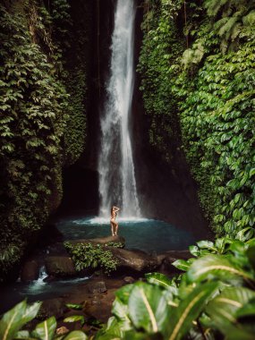 Scenic Leke leke waterfall and woman in bikini near waterfall.