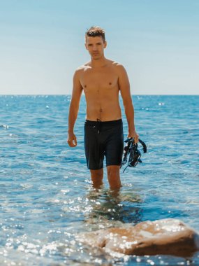 Yakışıklı sıska adam serbest dalıştan sonra sahilde eğleniyor..