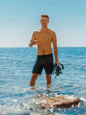 Okyanus sahilinde yakışıklı üstsüz erkek manken tatili. Daldıktan sonra gülümseyen sporcu erkek