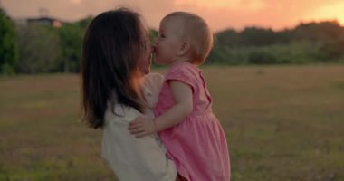 Mutlu anne ve tatlı kızı sıcak gün batımı tonlarıyla parkta.