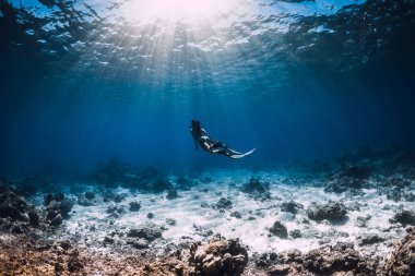 Kadın serbest dalgıç okyanusta suyun altında süzülüyor. Berrak sularda Freediver