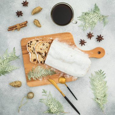 Ahşap bir tahta, çatal bıçak takımı ve gri masadaki kahve fincanının üzerindeki lezzetli kekin olduğu Noel kompozisyonu