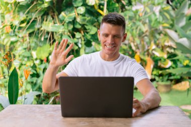 Neşeli bir adamın portresi dizüstü bilgisayarda görüntülü arama yapıyor..