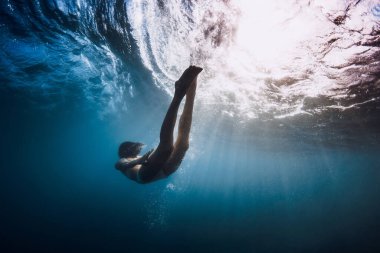 Kadın su altında yüzer okyanus dalgaları ve güneş ışınlarıyla.