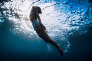 Kadınlar okyanus dalgaları ve güneş ışınlarıyla suyun altında yüzerler..