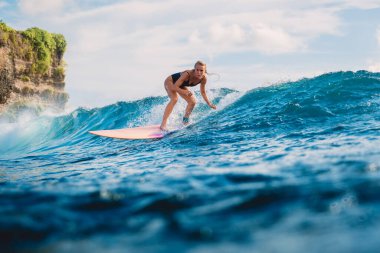 Sörfçü kız sörf tahtasında. Çekici sörfçü kadın ve mavi dalga