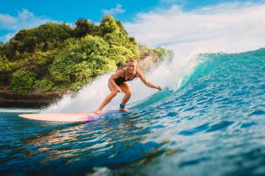 Okyanusta sörf tahtasında sörf yapan çekici sarışın kız. Sörf yaparken mavi dalgada sörfçü