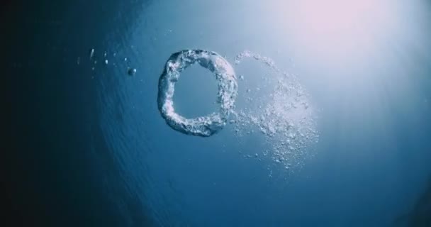 透明蓝色海洋中水下环状气泡和太阳光 — 图库视频影像