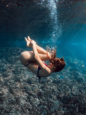 Şeffaf tropikal denizde poz veren, bikinili, mükemmel vücutlu bir kadın. Suyun altında rüya gibi görünüyorsun.
