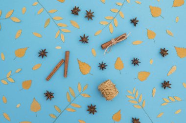 Şükran Günü ya da sonbahar kompozisyonu. Mavi arka planda sonbahar yaprakları ve tarçınlı. Düz yatış, üst görünüm.