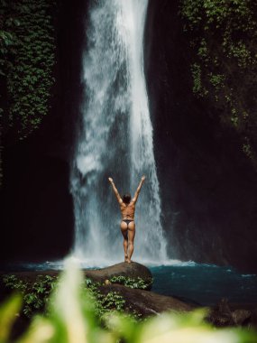 Manzaralı şelale ve bikinili mutlu kadın. Şelalede poz veren gezgin kız.