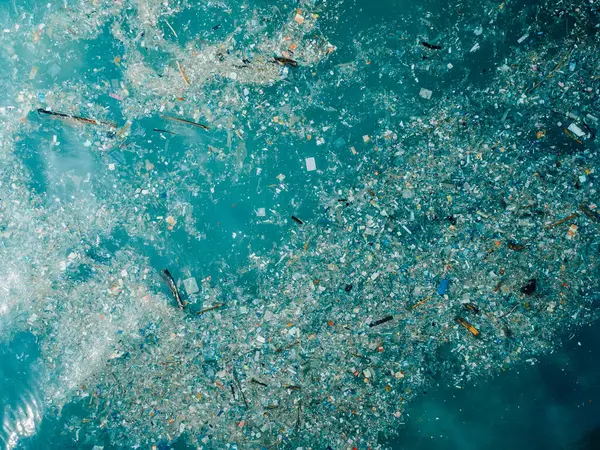 Ocean water and plastic trash in Bali island. Aerial view of pollution by plastic rubbish in marina
