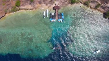 Bali 'deki Menjangan adasındaki mercan resifinin yanındaki mavi okyanusta turistik tekne ve iskele. Hava görünümü.